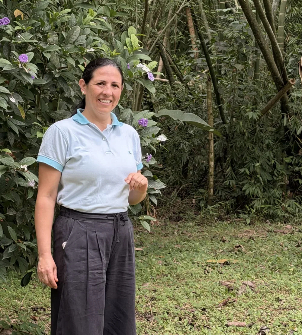 Sandra Grast sonriendo en un jardín, con camiseta celeste